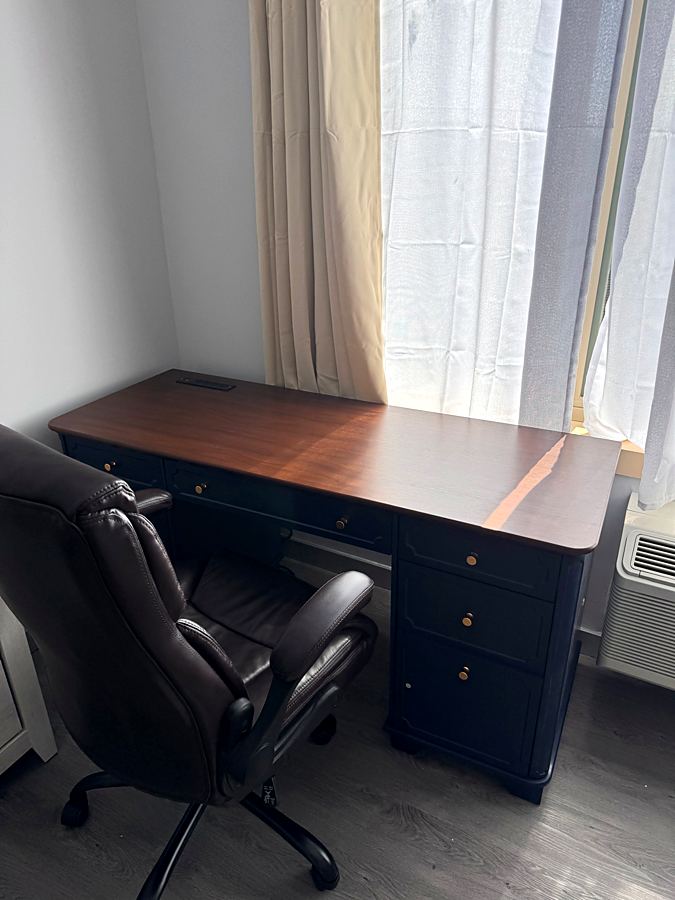 Assembled desk with drawers next to a window and an office chair