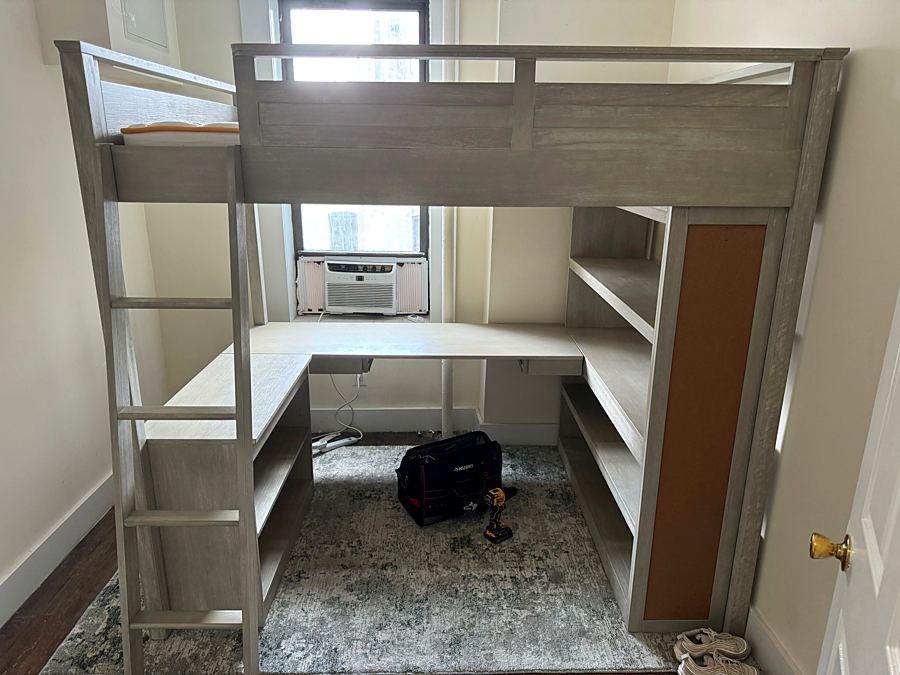 Assembled loft bed with desk, shelves, and a corkboard