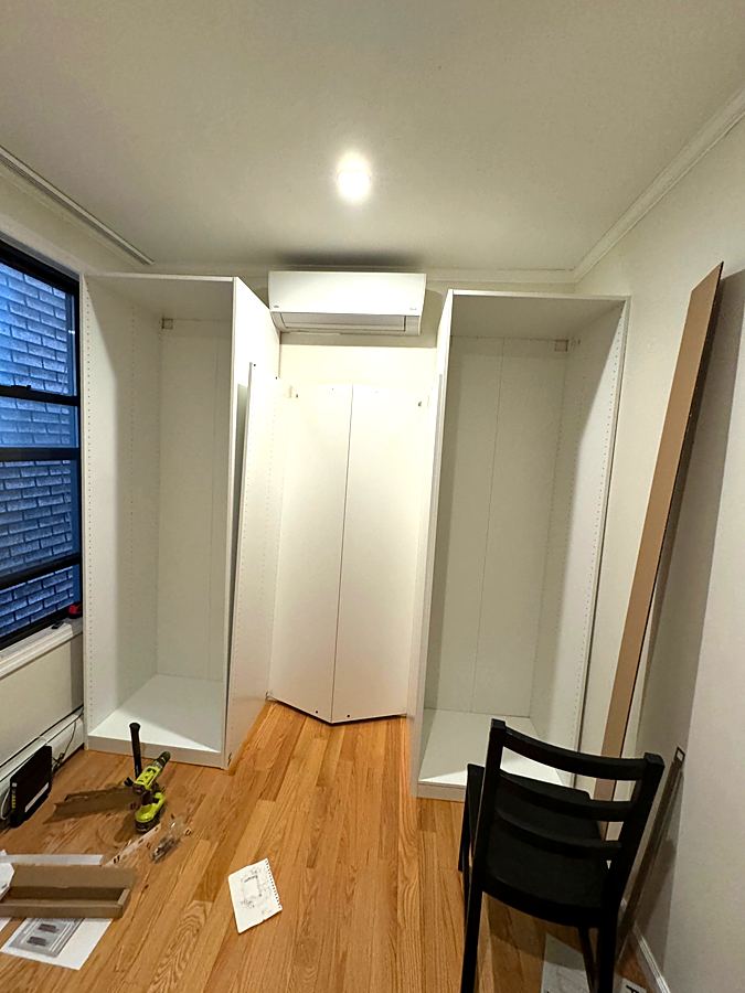 Tall white wardrobe frames being assembled in a bedroom